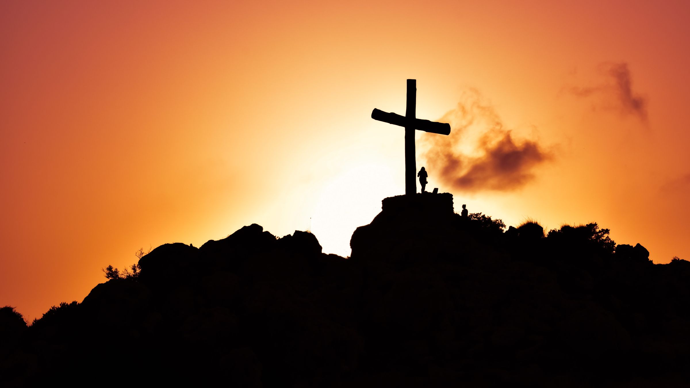 A cross on a hilltop silhouetted against a golden sunset