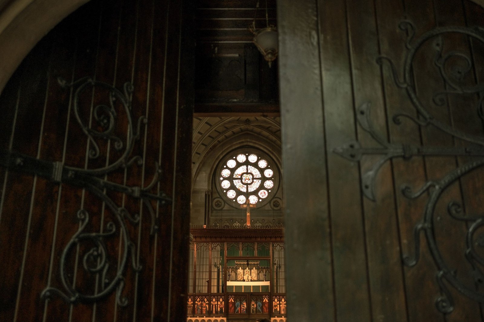 Looking through open wooden church doors toward a rose window