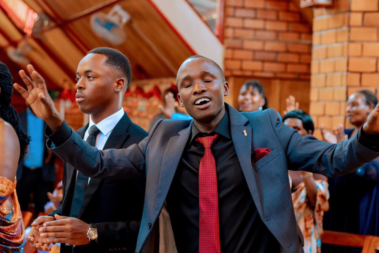 Young men worshipping joyfully with hands raised during a church service
